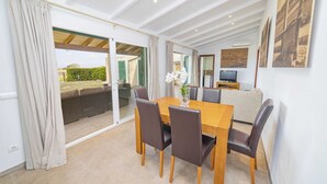 Un coin repas avec une table et des chaises en bois, un canapé et un téléviseur en arrière-plan.
