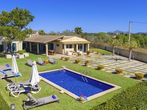 A residential property with a swimming pool, outdoor seating, and a view of the surrounding landscape.