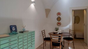 Un comedor con una mesa dispuesta para dos personas, un aparador verde y platos decorativos colgados en la pared.