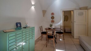Un comedor con una mesa redonda, sillas, un armario y platos decorativos colgados en la pared.