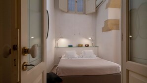 Un dormitorio con cama, lámparas de noche, una mesita y una silla.