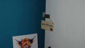 Una habitación con una pared azul, un radiador blanco, una puerta y un cartel que dice 'John O Groats'.