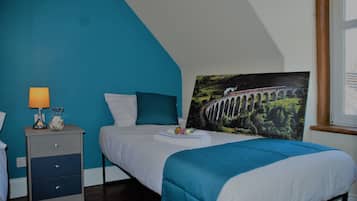 A bedroom with a bed, a nightstand, a lamp, and a painting of a bridge.