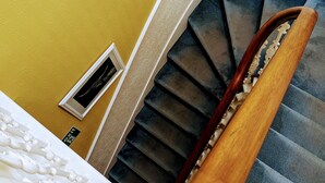 A staircase with a wooden handrail and a wall-mounted vent.