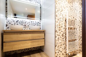 A bathroom with a wooden vanity, two sinks, a mirror, and a tiled backsplash. - TopParken Recreatiepark Beekbergen (Beekbergen)