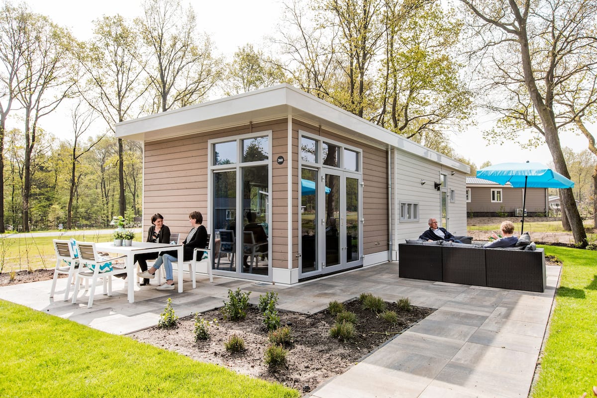 Un espace extérieur moderne, aménagé en patio, avec une table et des chaises pour les repas, un coin salon avec un canapé et un petit jardin avec de jeunes plantes.