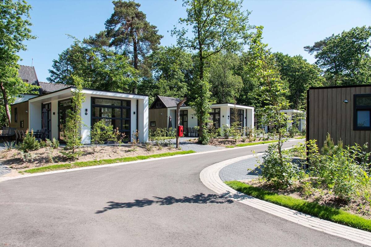 Un ensemble immobilier moderne composé de plusieurs bâtiments, avec une allée incurvée, le tout entouré de verdure et d’arbres.