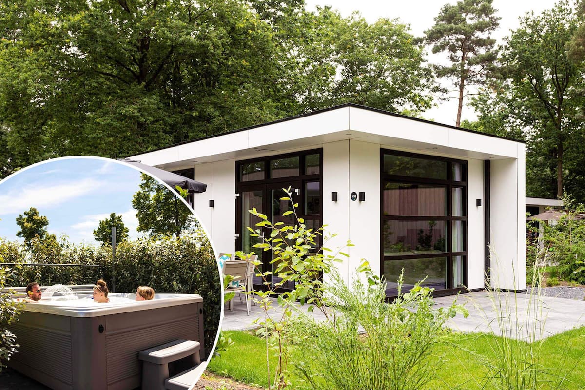 Une maison moderne à deux étages, dotée d’une grande porte vitrée et entourée d’une végétation luxuriante.