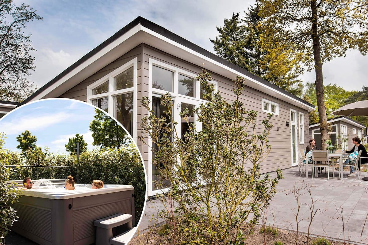 Une maison moderne dotée de grandes fenêtres, d’un patio avec mobilier d’extérieur et d’un jacuzzi.