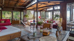 A spacious room with a high ceiling, wooden beams, and large windows offering a view of greenery outside. - AMORE RENTALS -Villa Era with Swimming Pool, Sea View, Terraces and Parking (Positano)