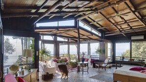 A spacious room with a high ceiling, large windows, and a bed. - AMORE RENTALS -Villa Era with Swimming Pool, Sea View, Terraces and Parking (Positano)