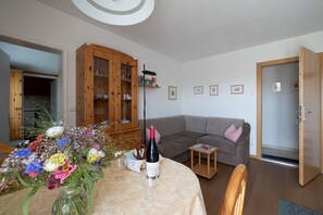 A living room with a dining table, a sofa, a cabinet, and a door.