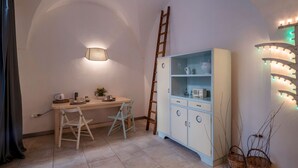 Una habitación acogedora con un escritorio, dos sillas, un aparador con puertas de cristal, una escalera y luces decorativas.