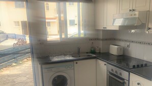 Une cuisine compacte équipée d’un lave-linge, d’un grille-pain et d’un four à micro-ondes.