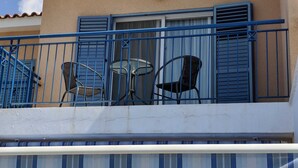Un balcon avec des balustrades bleues, deux chaises et une petite table.