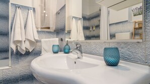 A bathroom with a white sink, two blue glass vases, and a mirror reflecting a shower area. - Apartment Cabo (Split)