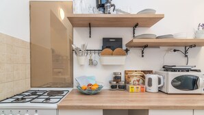 A kitchen with a gas stove, microwave, and various kitchen utensils and appliances. - Apartment Cabo (Split)