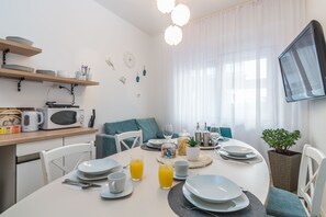 Zona de menjador moderna amb una taula rodona preparada per l'esmorzar, plats blancs i gots de suc d'aranja.