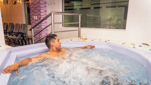 A man relaxing in a hot tub with a view of a tiled wall and a window. - Hotel Indio Inn (Otavalo)