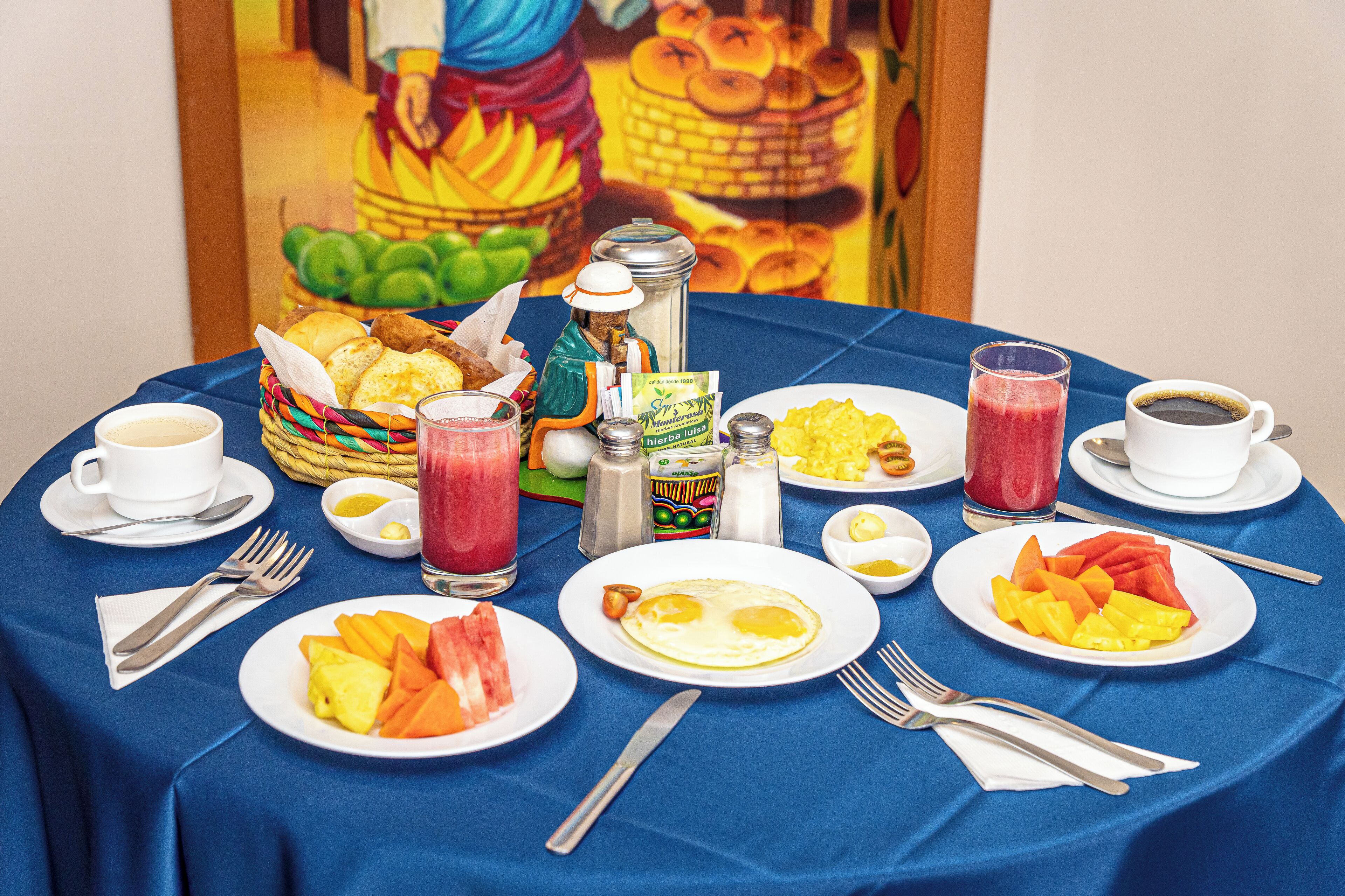 A breakfast table set with plates of food, beverages, and condiments.
