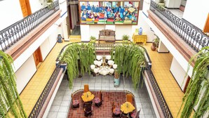 A spacious atrium with a central seating area, a large mural on the wall, and potted plants around the perimeter. - Hotel Indio Inn (Otavalo)