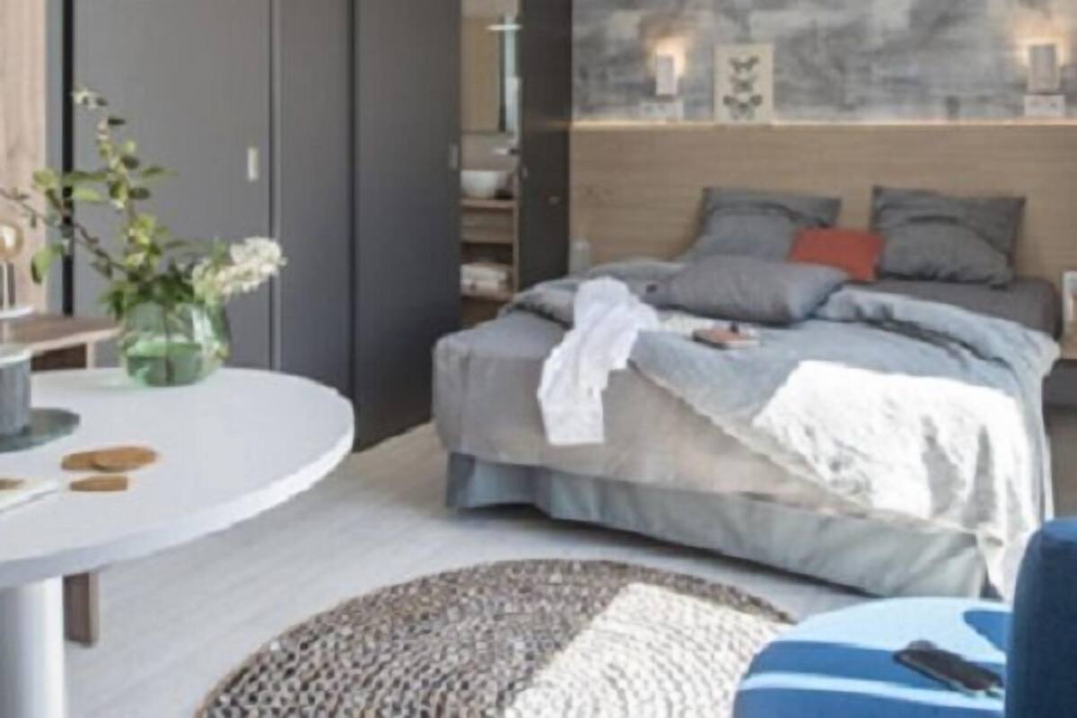 Un dormitorio con cama, mesita de noche y vistas a la ciudad a través de una ventana.
