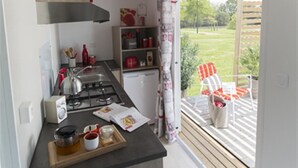Cuina amb fogó de gas, un rentapeus i un frigorífic petit. Hi ha una finestra que ofereix vistes a un jardí i zona d'estar a l'exterior.