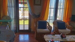 A room with wicker furniture, a glass table with a decorative cloth, and a view through a door to an outdoor area. - Beautiful bungalow with pool in the area of Los Llanos de Aridane (Los Llanos de Aridane)