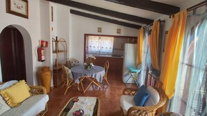 A living room with a sofa, chairs, a small table, and a kitchen area in the background. - Beautiful bungalow with pool in the area of Los Llanos de Aridane (Los Llanos de Aridane)