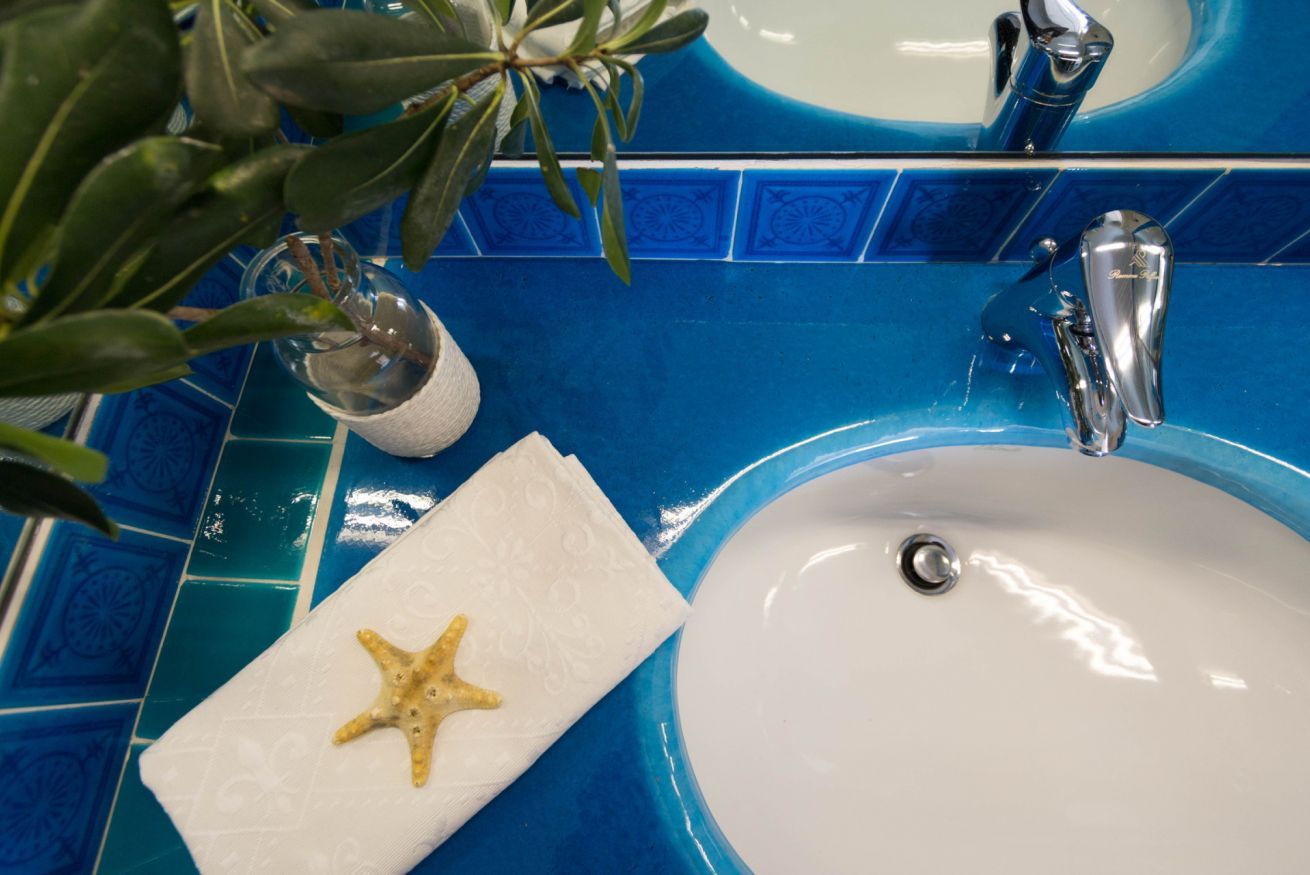 A bathroom with a blue tiled sink and a white towel with a starfish.