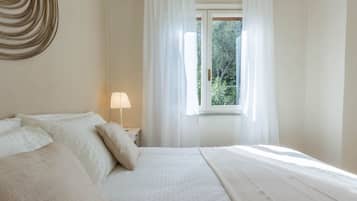 A bedroom with a bed, a nightstand, a lamp, and a window with curtains.