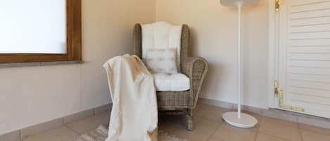 A room with a wicker chair, a white floor lamp, and a white door.