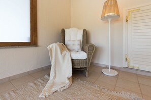 Ein Zimmer mit einem Korbstuhl, einer weißen Stehlampe und einer weißen Tür.