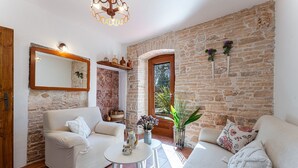 Una sala de estar acogedora con pared de piedra, dos sofás blancos, una mesita redonda y una puerta de madera.