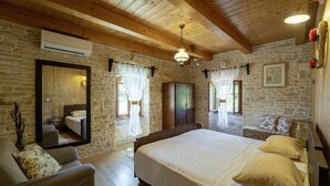 Un dormitorio con una cama grande, techo de madera, paredes de piedra y un espejo.
