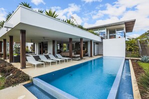 Un espace moderne aménagé au bord de la piscine, avec des chaises longues et une piscine à l’eau d’un bleu cristallin.