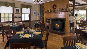 Un restaurante acogedor con mesas y sillas de madera, una chimenea de ladrillo y adornos festivos.