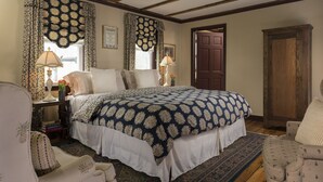 Un dormitorio tradicional con una cama grande, un armario de madera y una alfombra estampada.