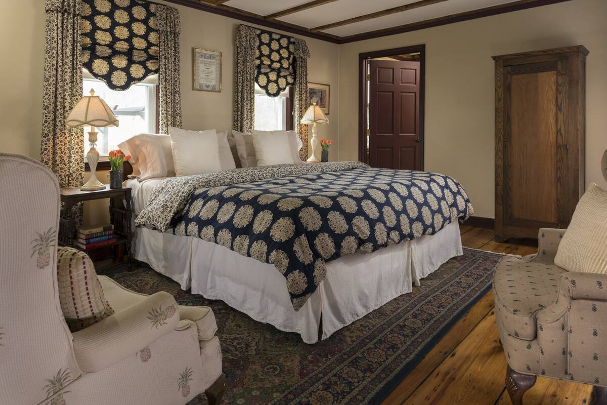 A traditional bedroom with a large bed, a wooden wardrobe, and a patterned rug.