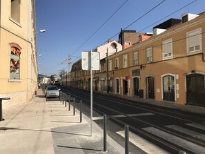 Eine Straße mit Gebäuden, einem Zebrastreifen und einer Straßenbahnlinie.