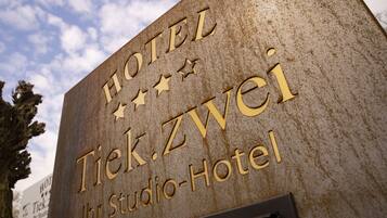 Un letrero del Hotel Tiek Zwei Studio con superficie texturizada y letras doradas.