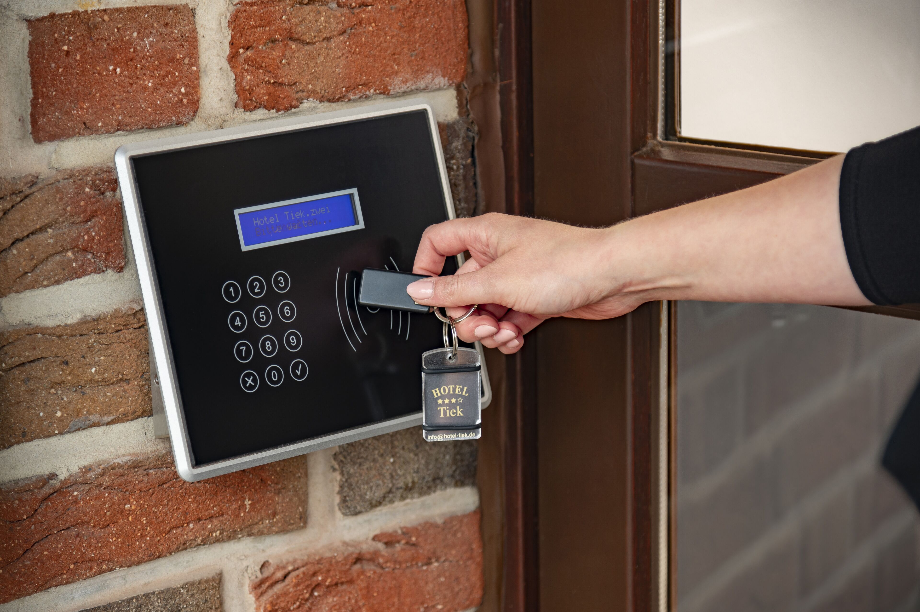 Een hand steekt een sleutel in het keypad-slot van een hotel.