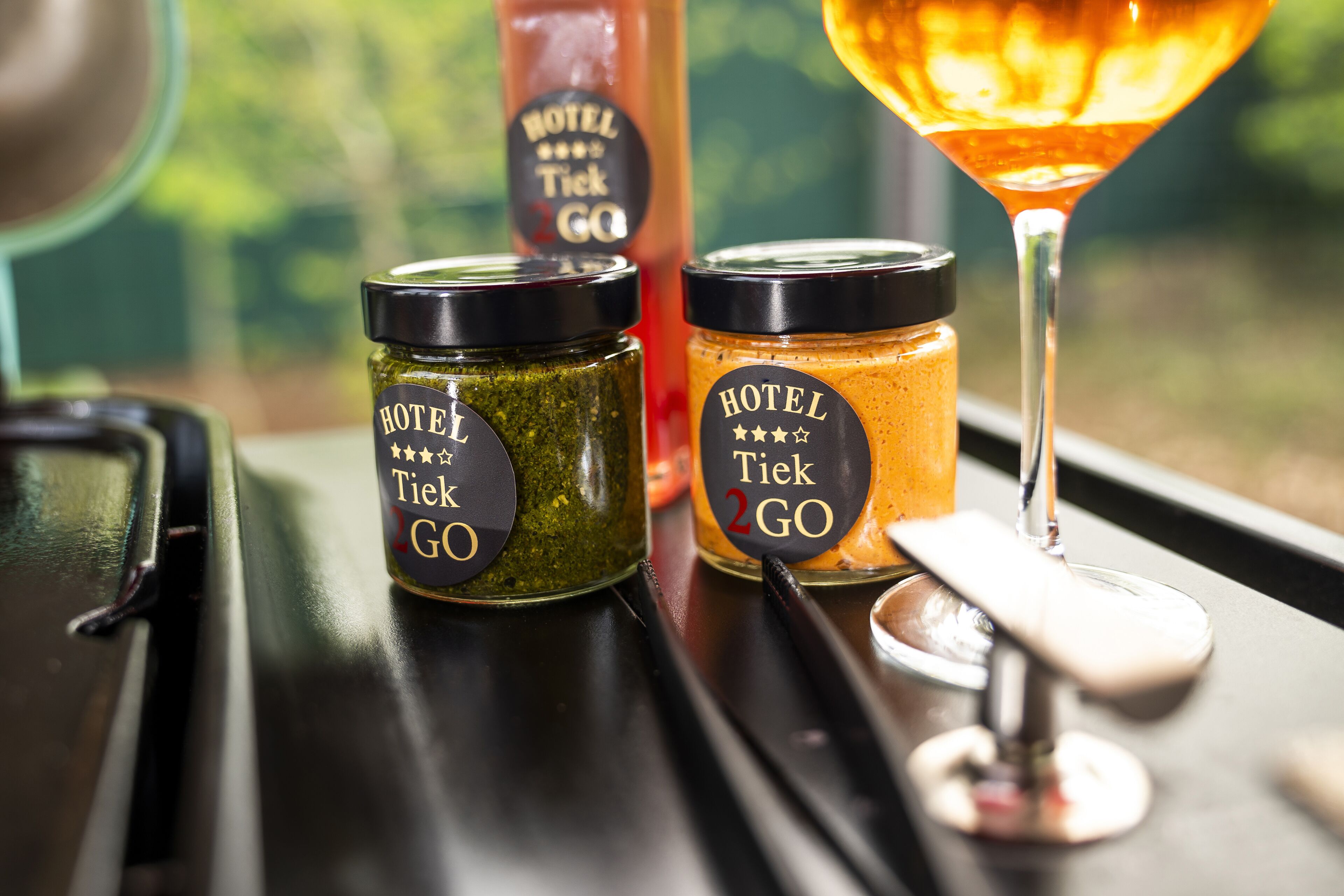 Two jars labeled 'Hotel Tiek 2GO' on a table with a martini glass.