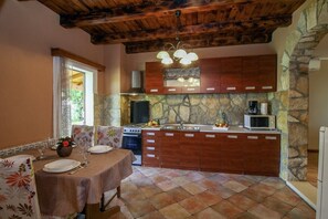 Cozy kitchen with stove, microwave, and coffee maker, complemented by a dining area with table for two.