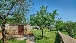 A stone building with a metal door, surrounded by a stone wall and lush greenery. - Holiday home Orihi * 2000 m2 fenced garden, covered terrace, BBQ (Barban)