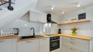 A modern kitchen with white cabinets, a black stove, and a wooden countertop. - Holiday home Orihi * 2000 m2 fenced garden, covered terrace, BBQ (Barban)