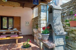 A stone fireplace with a bench and potted plants nearby. - Holiday home Orihi * 2000 m2 fenced garden, covered terrace, BBQ (Barban)