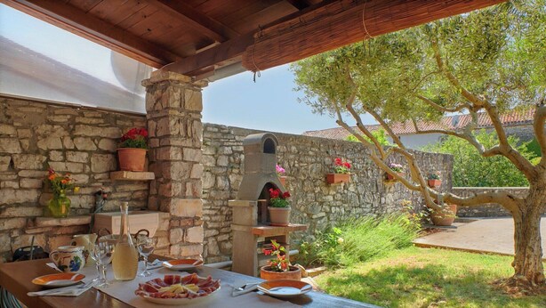 An outdoor dining area with stone walls, wooden beams, and potted plants. - Holiday home Orihi * 2000 m2 fenced garden, covered terrace, BBQ (Barban)