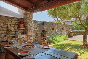 An outdoor dining area with stone walls, wooden beams, and potted plants. - Holiday home Orihi * 2000 m2 fenced garden, covered terrace, BBQ (Barban)