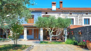 A stone building with a tiled roof, a central courtyard with a tree, and a stone wall with potted plants. - Holiday home Orihi * 2000 m2 fenced garden, covered terrace, BBQ (Barban)